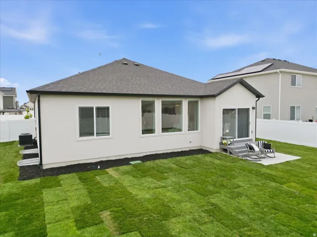 Rear exterior featuring a patio with steps, sliding glass door access, white vinyl fencing, and a newly sodded lawn
