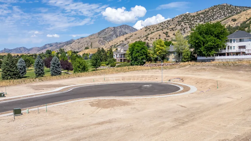 Cleared building lot featuring a paved cul-de-sac, curb, and visible utility connections