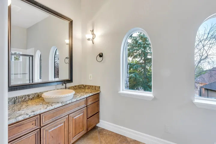 Bathroom vanity with a vessel sink, stone countertop, and wood-finish cabinetry