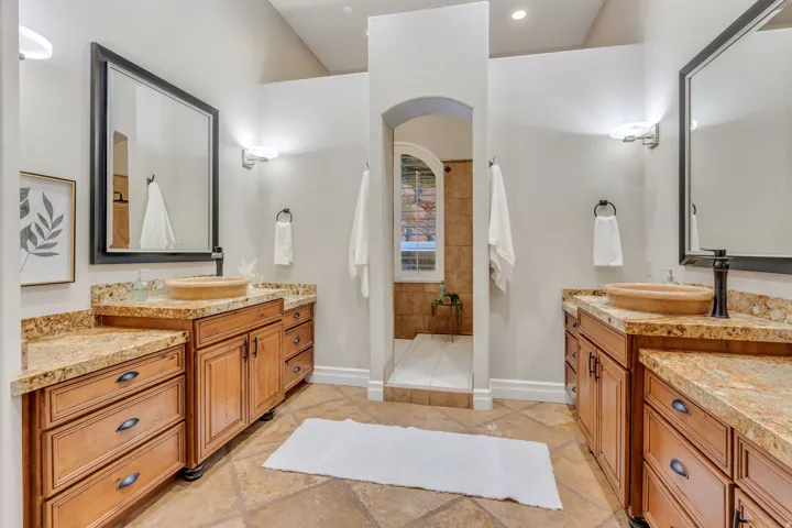 Dual wood-finish vanities featuring granite countertops and vessel sinks