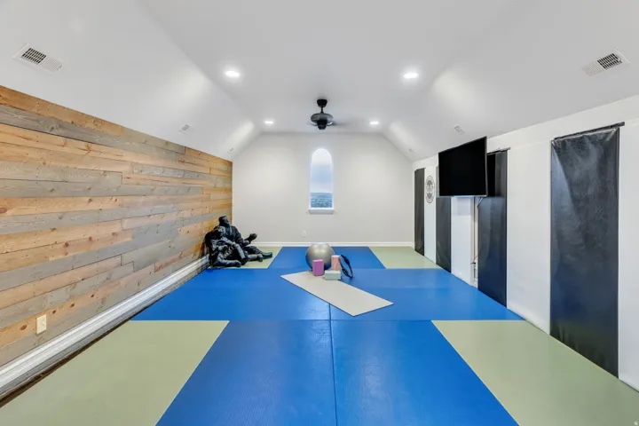 Expansive bonus room featuring sloped ceilings with recessed lighting, a modern ceiling fan, and a unique arched window