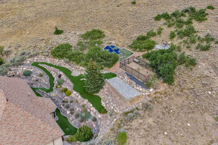 Terraced landscape design featuring artificial turf pathways, mature evergreen trees, and integrated rockery