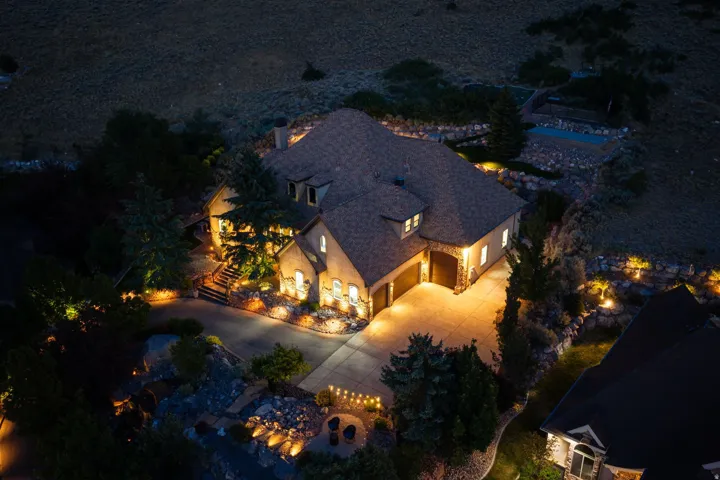 Multi-story residence featuring a stone and stucco exterior, prominent gabled roofline, and attached two-car garage with wood-finish doors