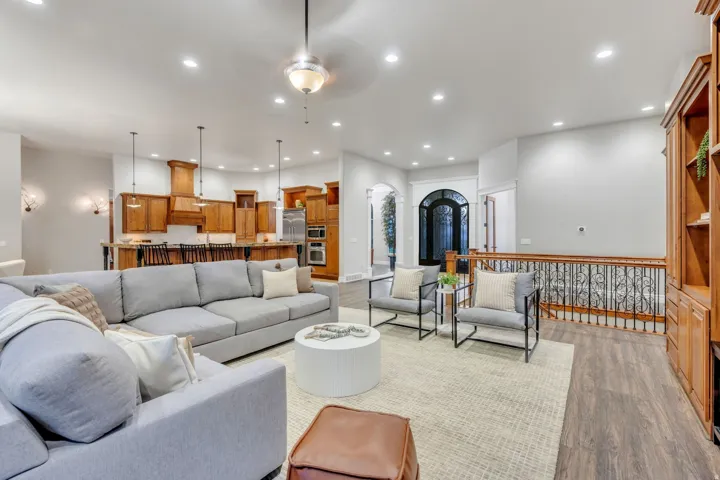 Open-concept living area with wood-finish flooring, recessed lighting, and a built-in wood cabinetry unit