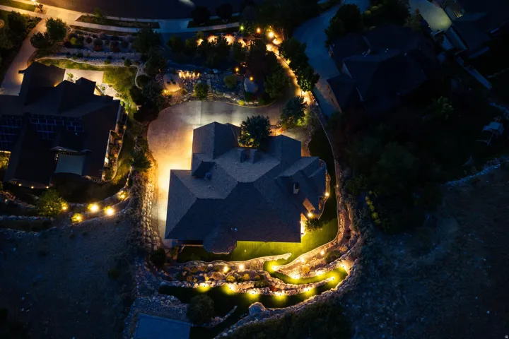 Expansive property featuring a paved driveway, mature landscaping, and extensive exterior lighting