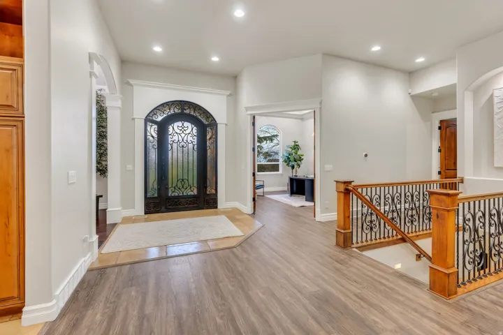 Grand entryway featuring a wrought iron double door with arched transom, contrasting tile flooring, and recessed lighting