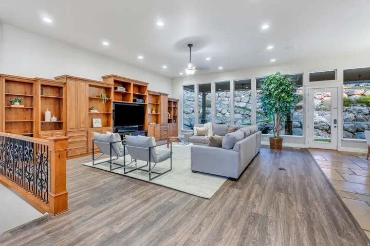 Spacious living area featuring extensive built-in wooden cabinetry, recessed lighting, and wood-finish flooring