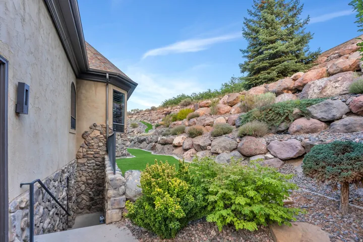 Terraced landscaping with natural rock formations, artificial turf pathways, and mature evergreen plantings