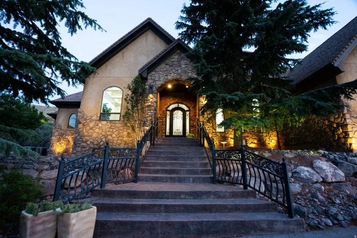 Stone and stucco exterior with arched windows, prominent stone stairs with ornate iron railings, and a grand arched entry door with decorative ironwork