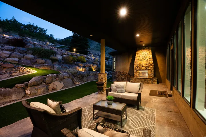 Covered patio featuring a stone fireplace, recessed lighting, and expansive floor-to-ceiling windows