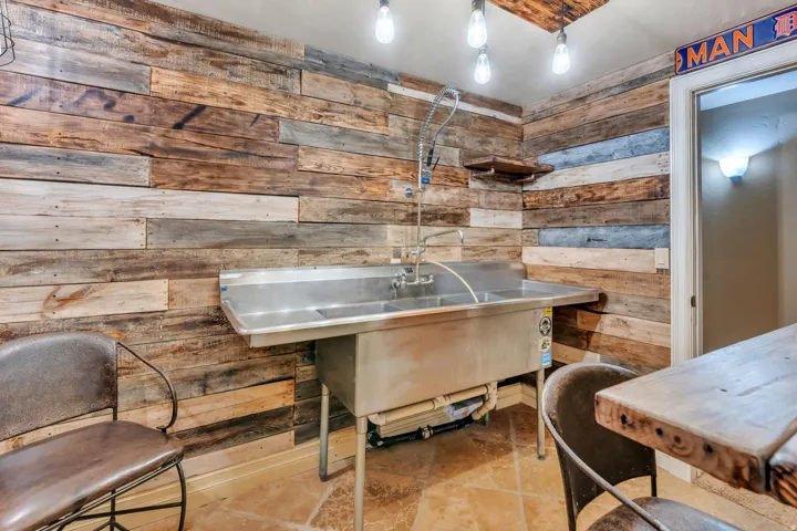 Reclaimed wood-paneled accent wall featuring a stainless steel utility sink with a high-arc faucet