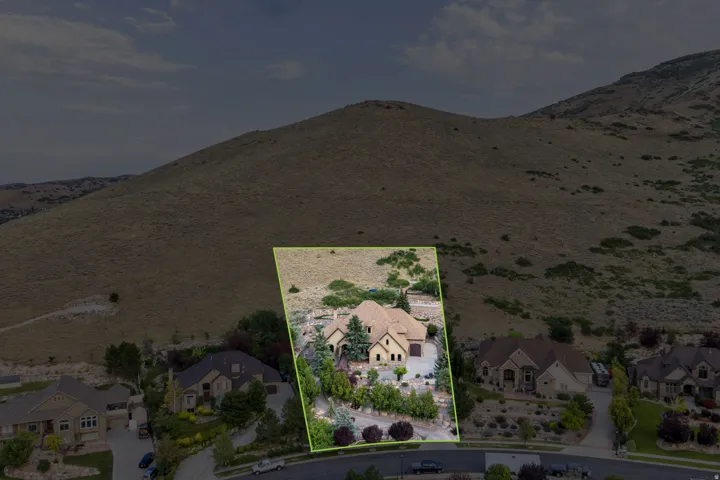 Hillside property with extensive landscaping, mature trees, and a multi-level stone facade
