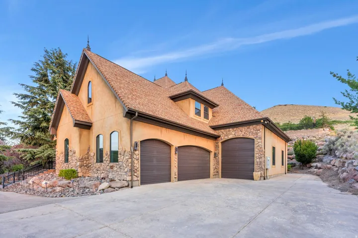 Stucco and stone exterior featuring multiple arched windows and a multi-car garage with arched doors
