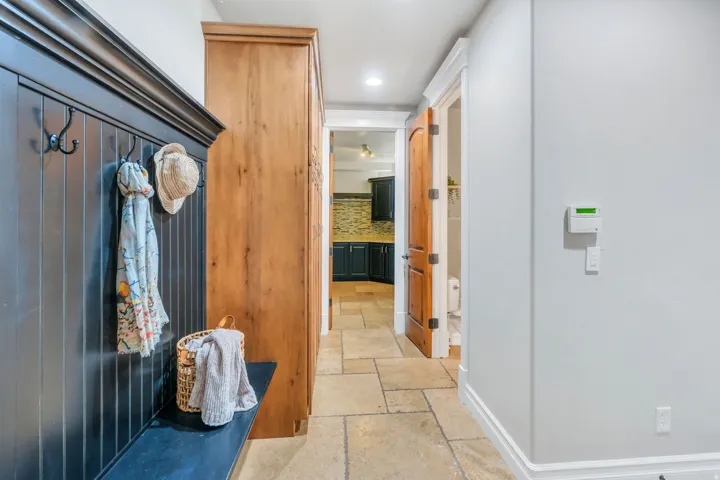 Entryway mudroom bench with beadboard paneling and integrated hooks, complemented by a tall wood-finish storage cabinet