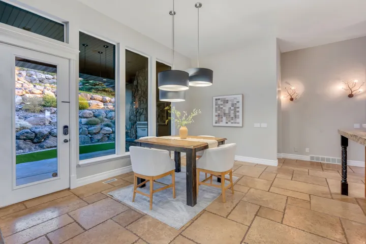 Dining area featuring rectangular stone tile flooring, a glass-paned exterior door, and multiple tall windows