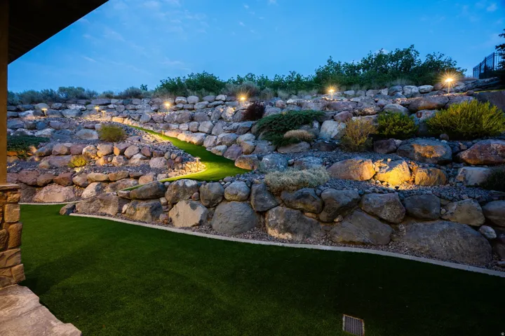 Expansive rock retaining wall with integrated landscape lighting