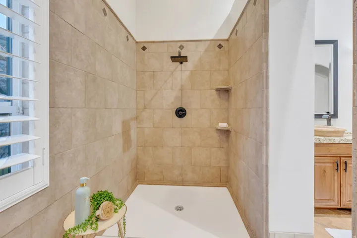 Tiled shower with a white base, matte black fixtures, and integrated shelving