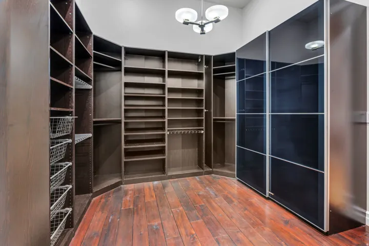 Custom closet system featuring dark wood-finish cabinetry, integrated shelving, and sliding glass doors