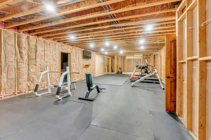 Expansive unfinished basement featuring exposed wood framing, ceiling joists, and recessed lighting