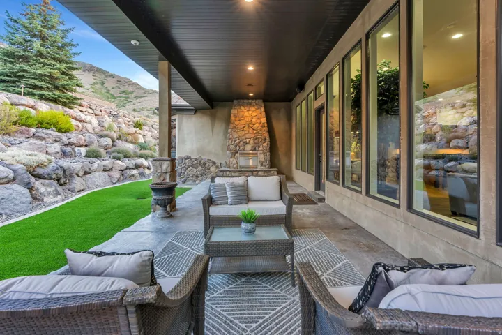 Covered outdoor patio featuring a stone fireplace, recessed lighting, and large windows