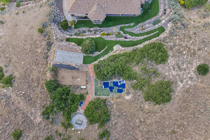 Terraced landscape featuring a stone retaining wall, artificial turf, and a circular stone patio with a central fire pit