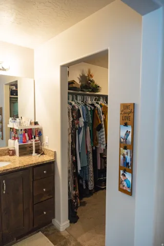 Vanity area featuring a single sink, stone-look countertop, dark wood-finish cabinetry, and an integrated mirror