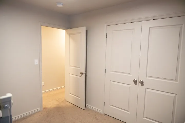 Neutral-toned wall paint with white trim, carpeting, and double-panel closet doors