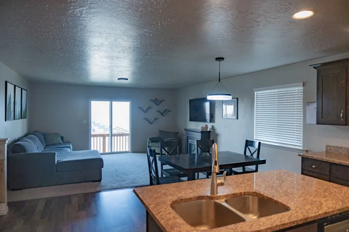 Kitchen counter with dual-basin stainless steel sink and speckled countertop overlooking a combined living and dining area