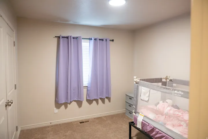 Carpeted room featuring a window with blinds, a flush mount ceiling light, and a paneled interior door