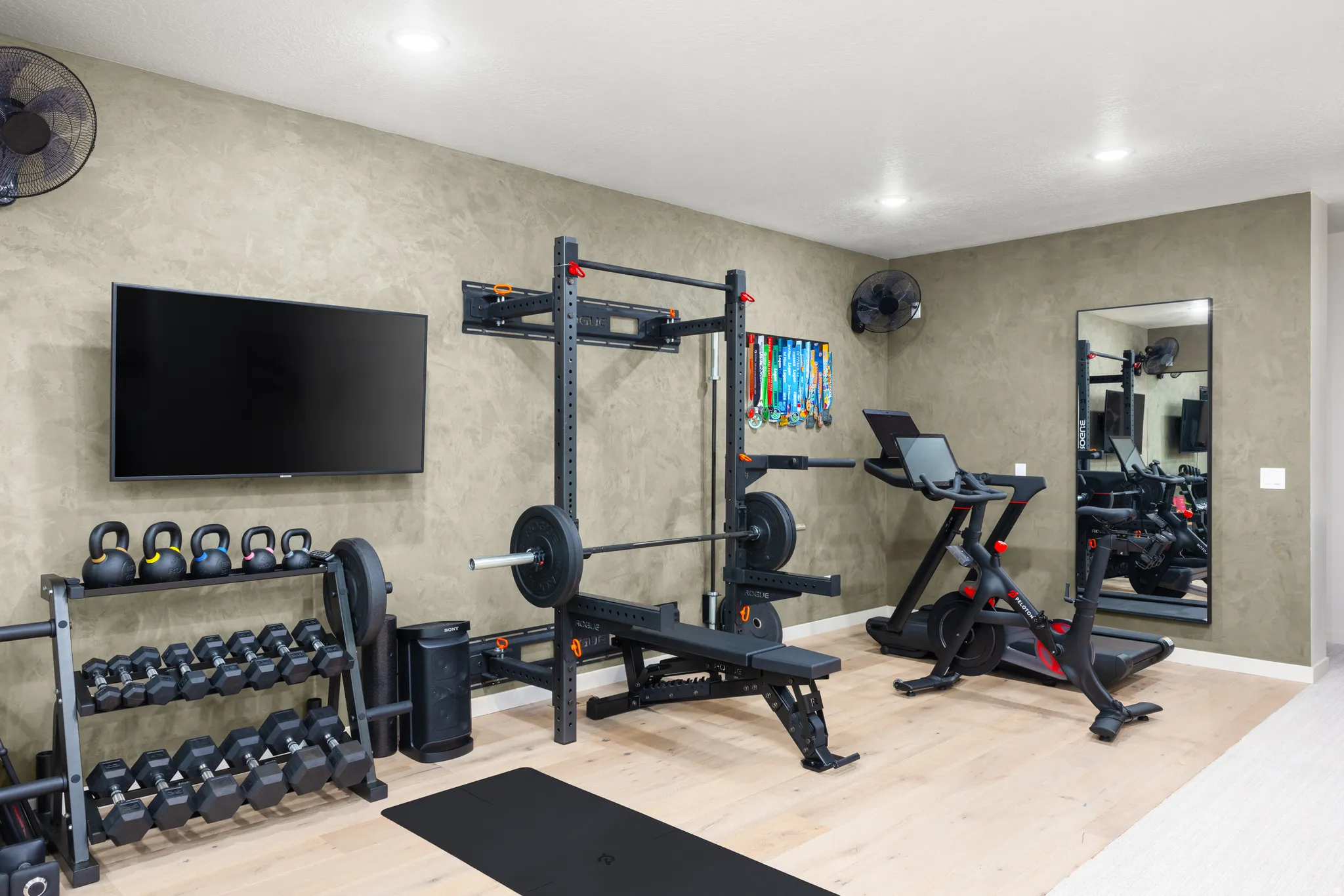 Dedicated fitness area featuring light wood-finish flooring, textured wall finishes, and recessed lighting