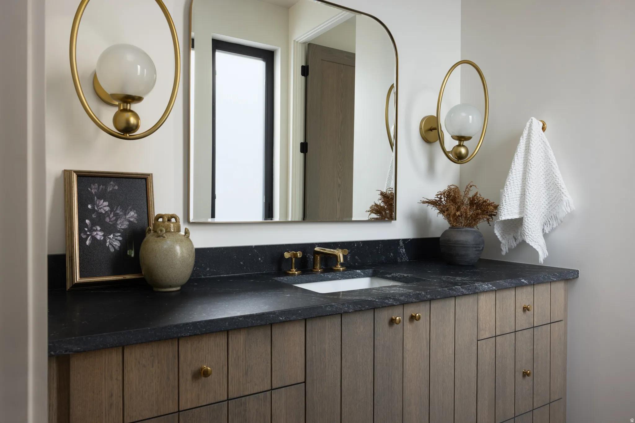 Bathroom vanity featuring a dark countertop, an undermount sink, and a gold-toned faucet