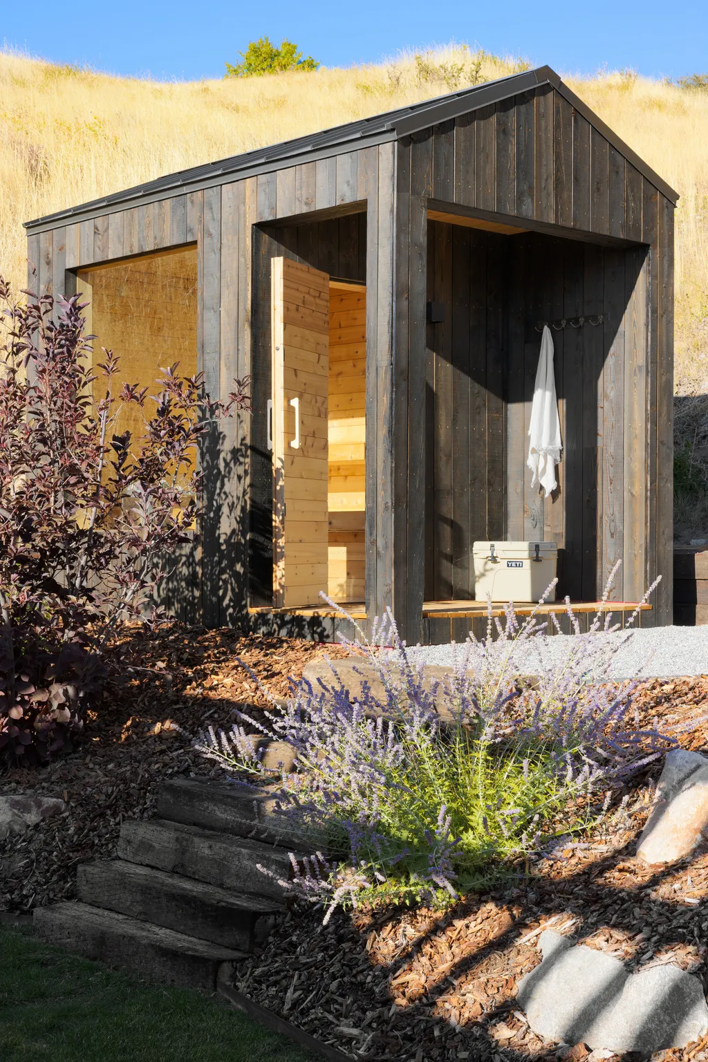 Rustic wood-clad auxiliary structure with a gabled roofline and open-air alcove