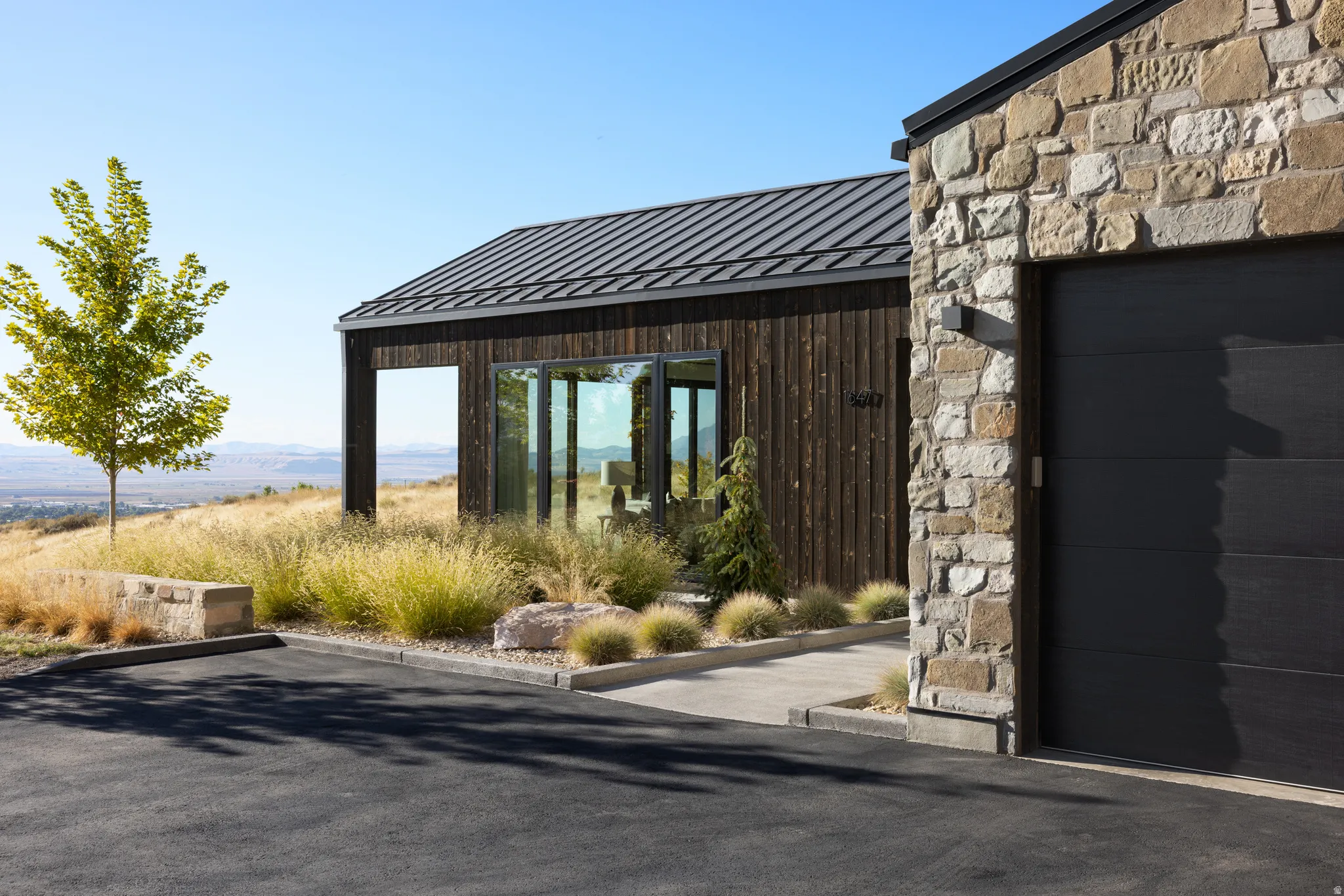 Contemporary exterior featuring a metal roof, dark wood siding, and stone accents