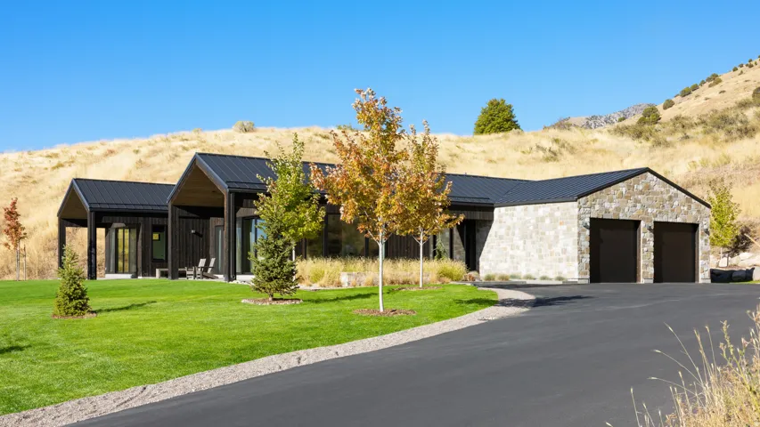 Modern residence featuring a black metal roof and natural stone siding