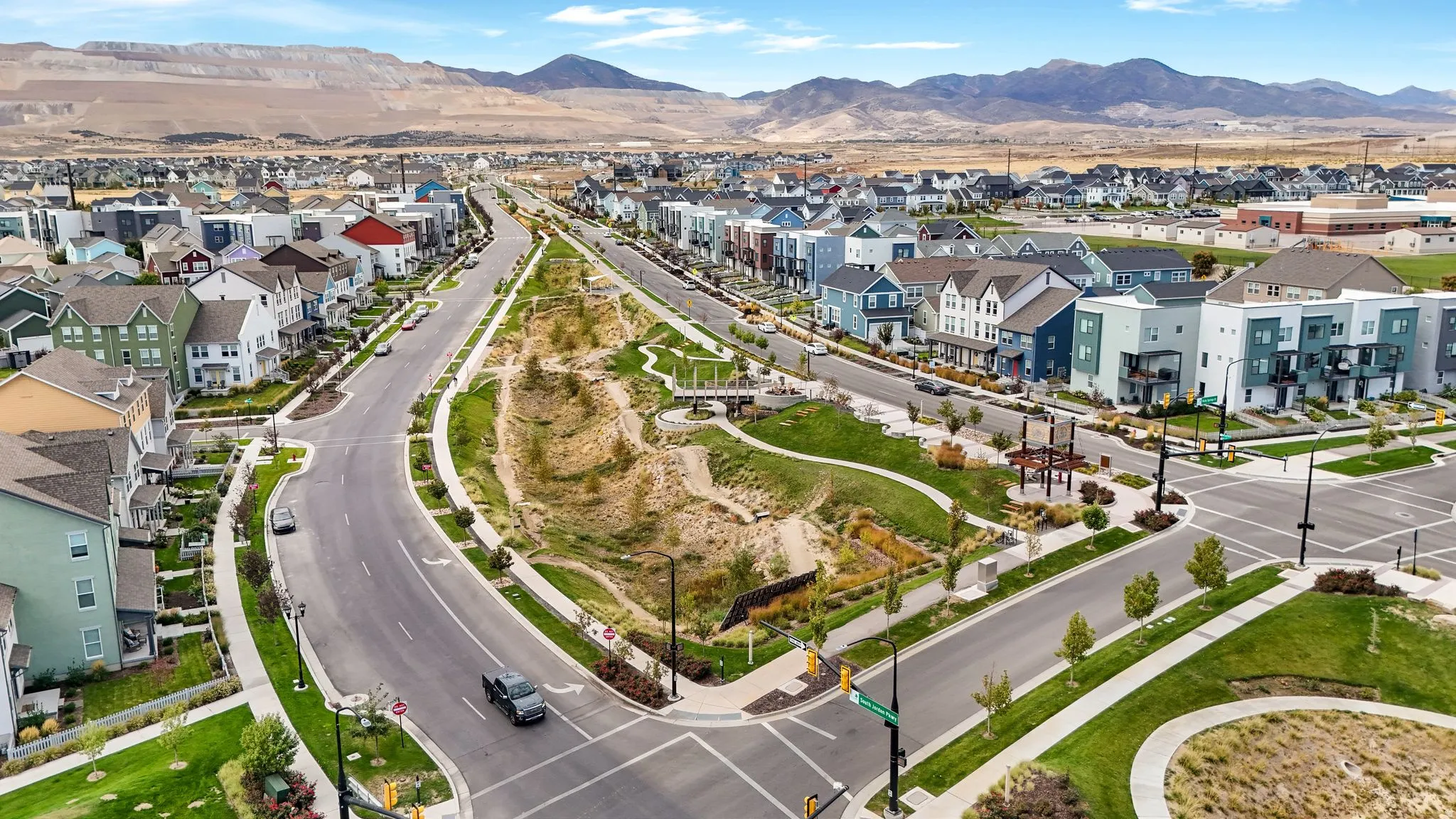 Aerial view showcasing a community with diverse architectural styles, integrated green spaces, and mountain scenery