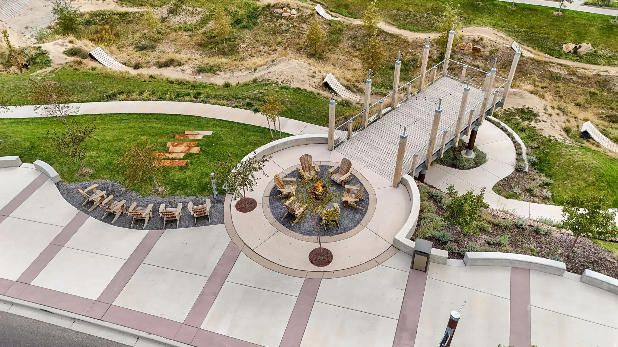 Outdoor communal fire pit area featuring a circular concrete patio, surrounding seating, and a decorative pebble ground cover