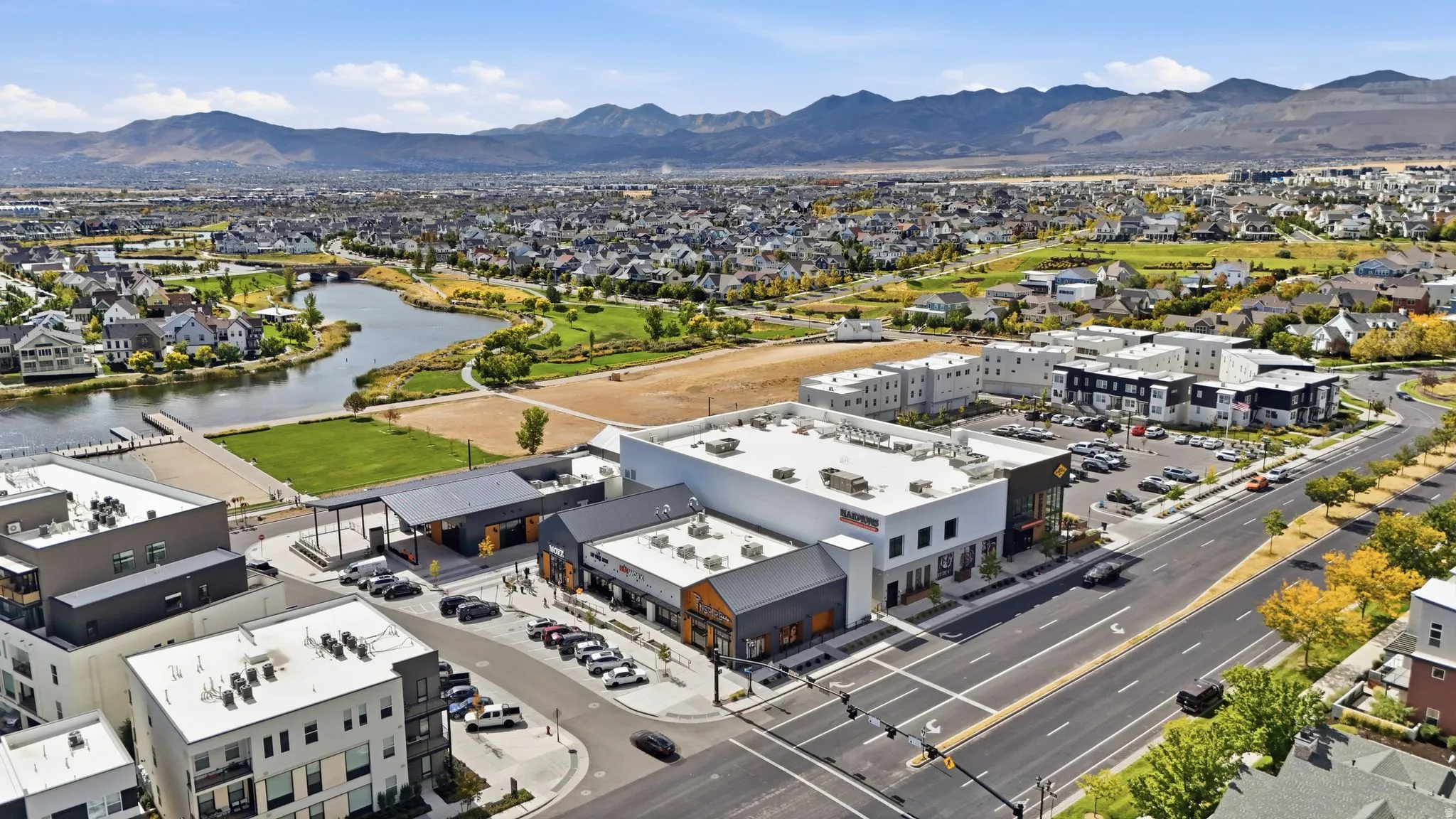 Aerial perspective showcasing a mixed-use development with commercial buildings, residential structures, and a prominent waterway
