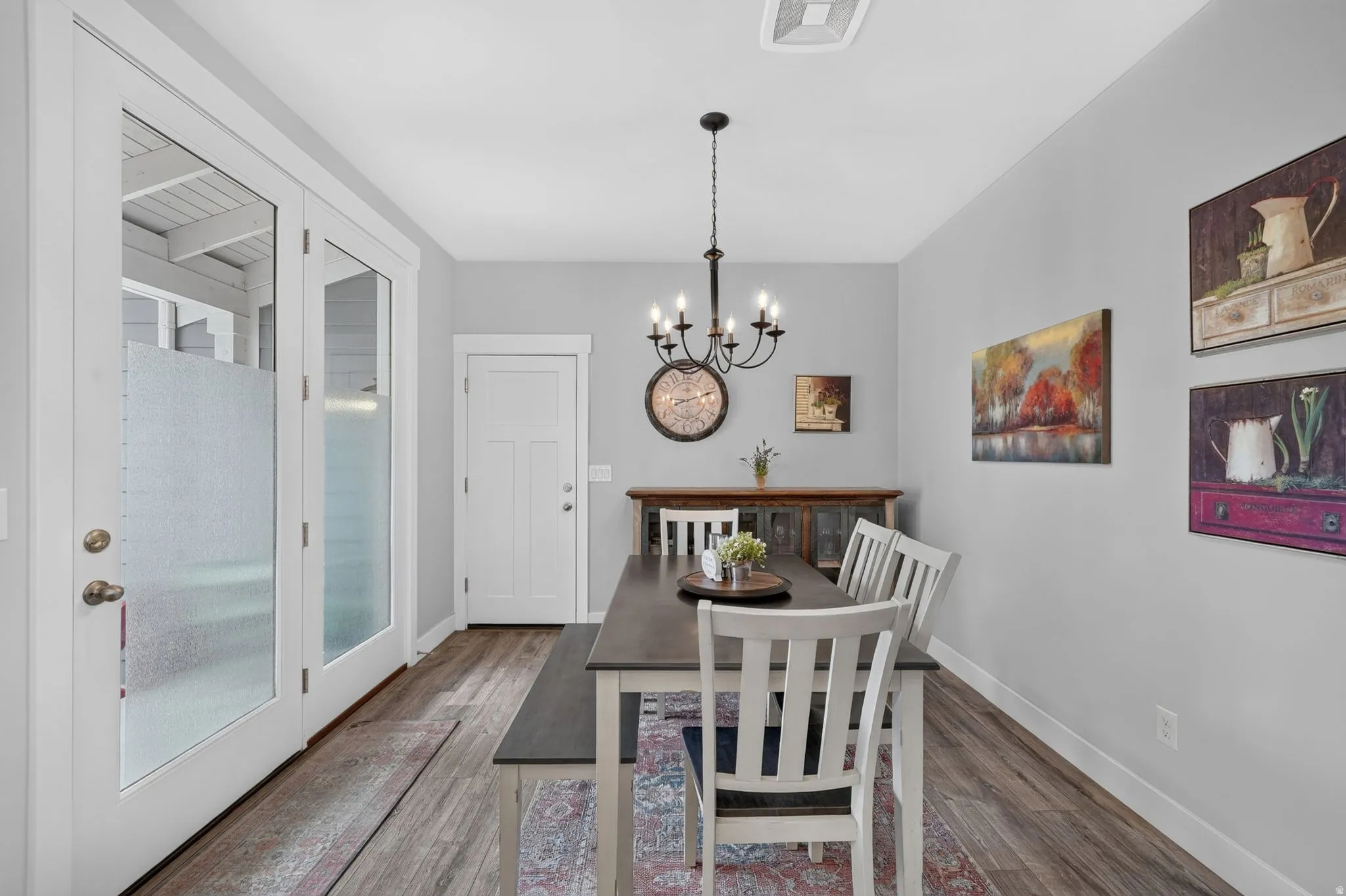 Dining area featuring wood-finish flooring, a contemporary chandelier, and light gray wall paint