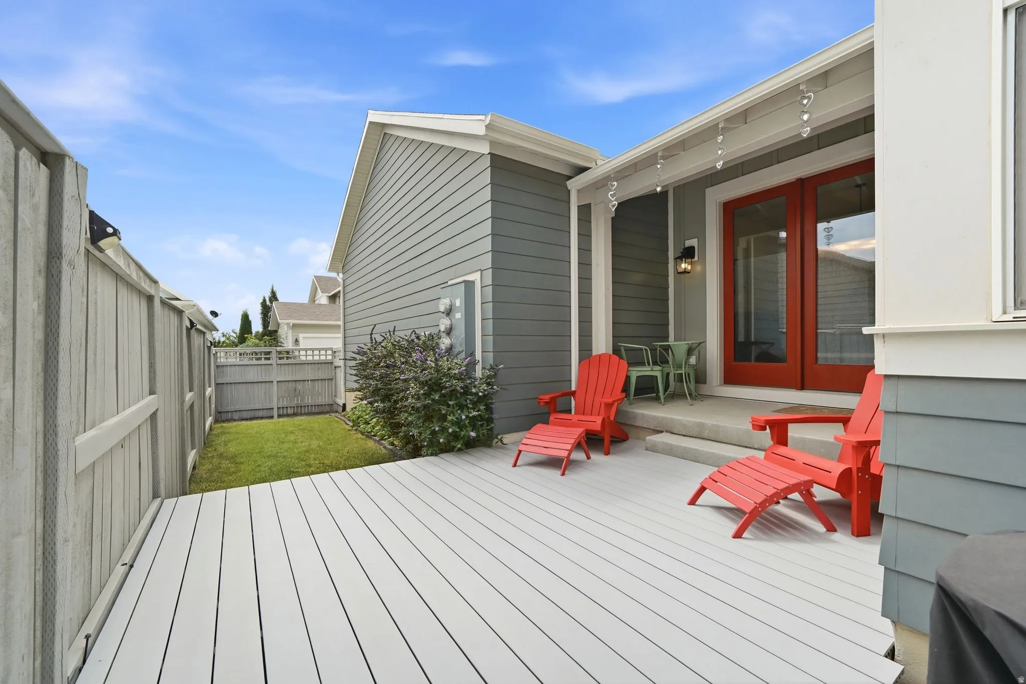Spacious outdoor deck with light gray plank flooring, bordered by a wooden privacy fence