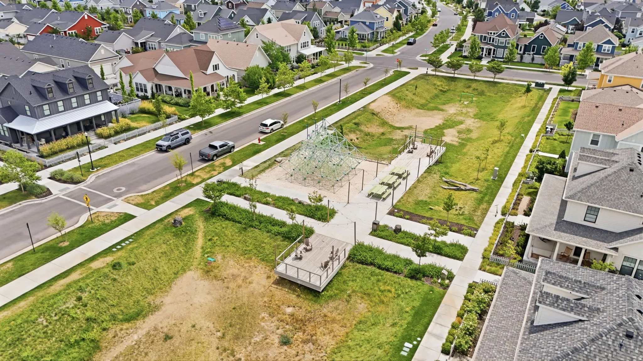 Expansive green space featuring a contemporary climbing structure, paved pathways, multiple seating areas, and a dedicated viewing platform