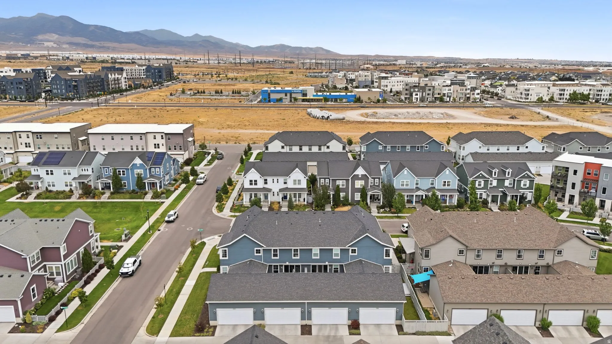 Modern residential community featuring diverse architectural styles, integrated green spaces, and mountain backdrops