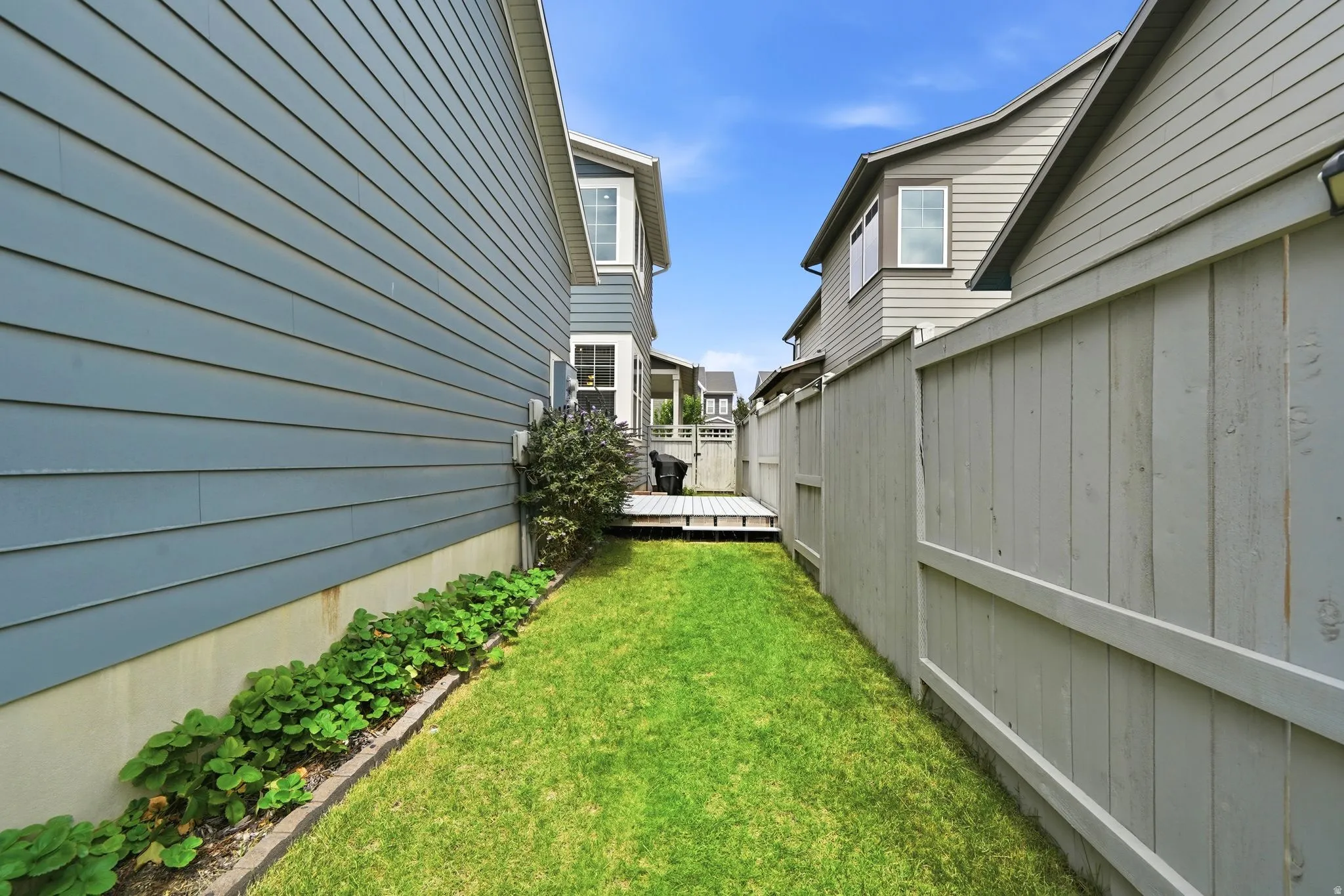 Grassed side yard featuring a wooden privacy fence and established shrubbery