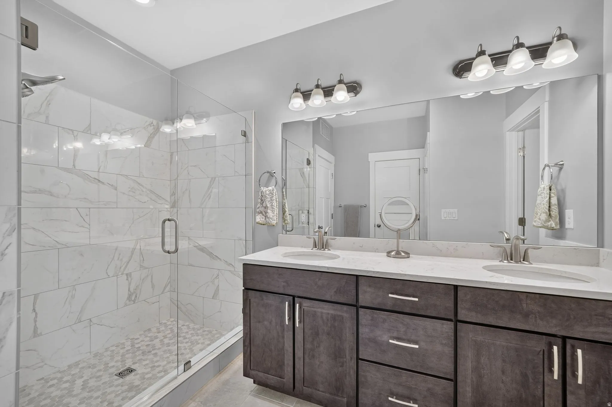 Dual sink vanity with dark wood-finish cabinetry, light-toned countertops, and brushed nickel hardware