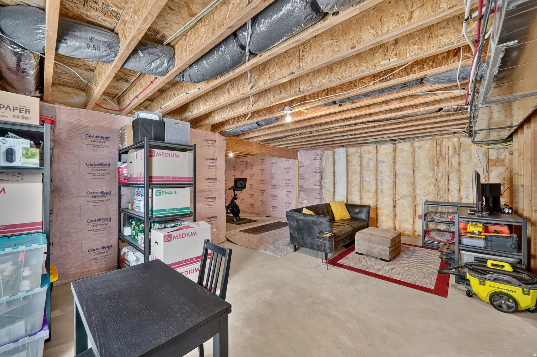 Unfinished basement featuring exposed wood joists, insulation, and concrete flooring