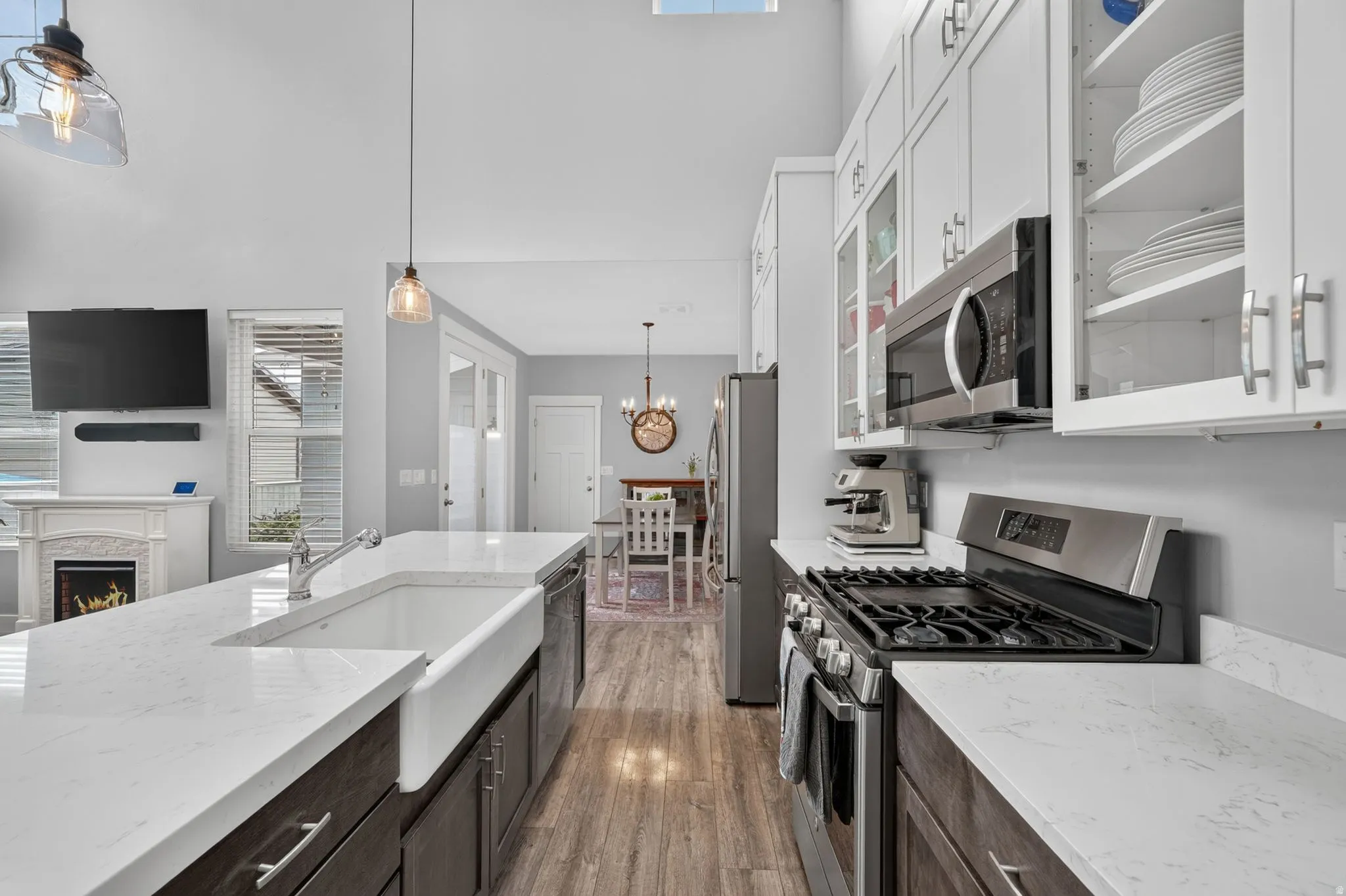 Gourmet kitchen with wood-finish flooring, quartz countertops, a farmhouse sink, stainless steel appliances, and ceiling-height cabinetry