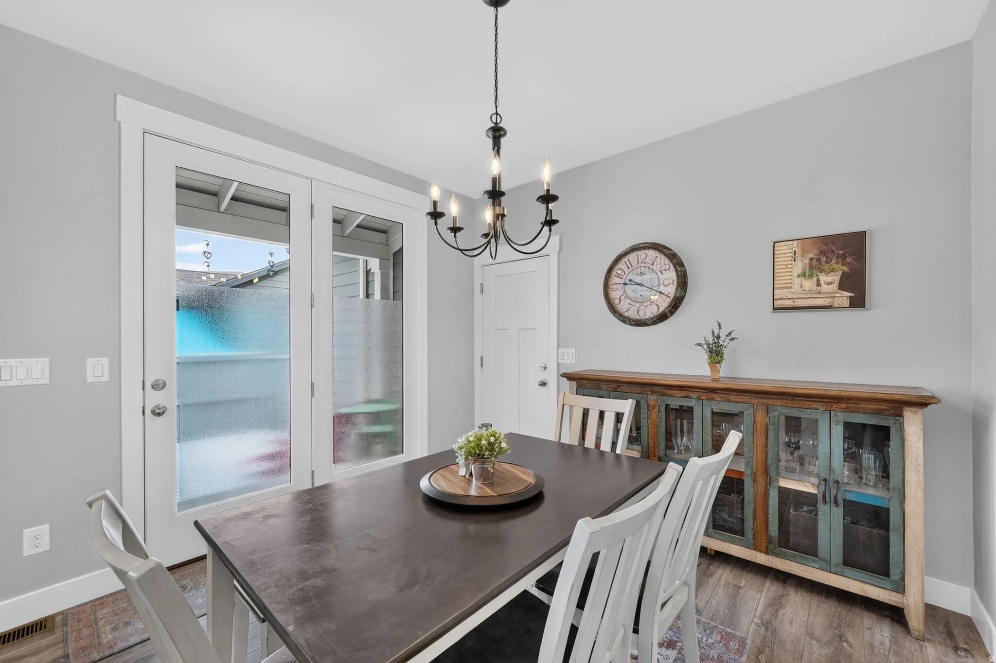Dining area featuring wood-finish flooring, a contemporary chandelier, and French doors leading to an exterior space