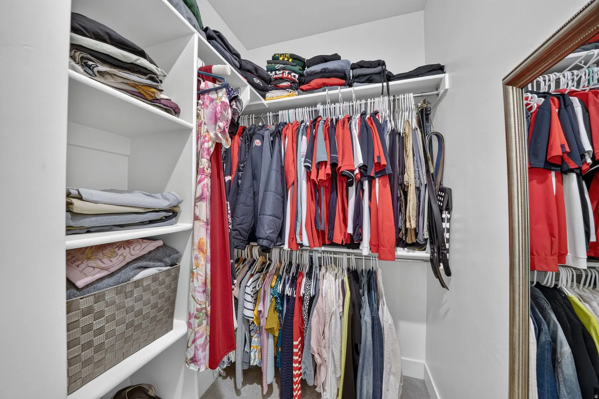 Walk-in closet featuring built-in shelving, two levels of hanging rods, and a full-length mirror with a decorative frame
