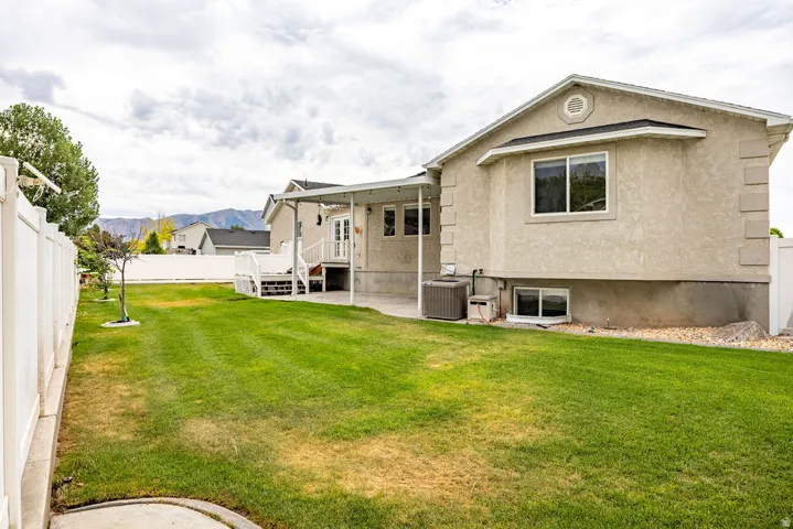 Spacious backyard featuring a lawn, a full white vinyl privacy fence, and a covered back patio with a white deck