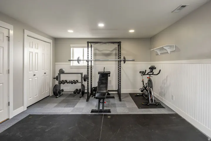 Dedicated fitness space featuring recessed lighting, a window, wainscoting, and durable flooring with a rubber mat section