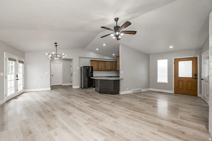 Expansive living area featuring light wood-finish flooring, vaulted ceilings, and recessed lighting